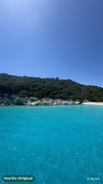 A turquoise cove with a green wooded hill on the shore, Ionian Islands, Greece.