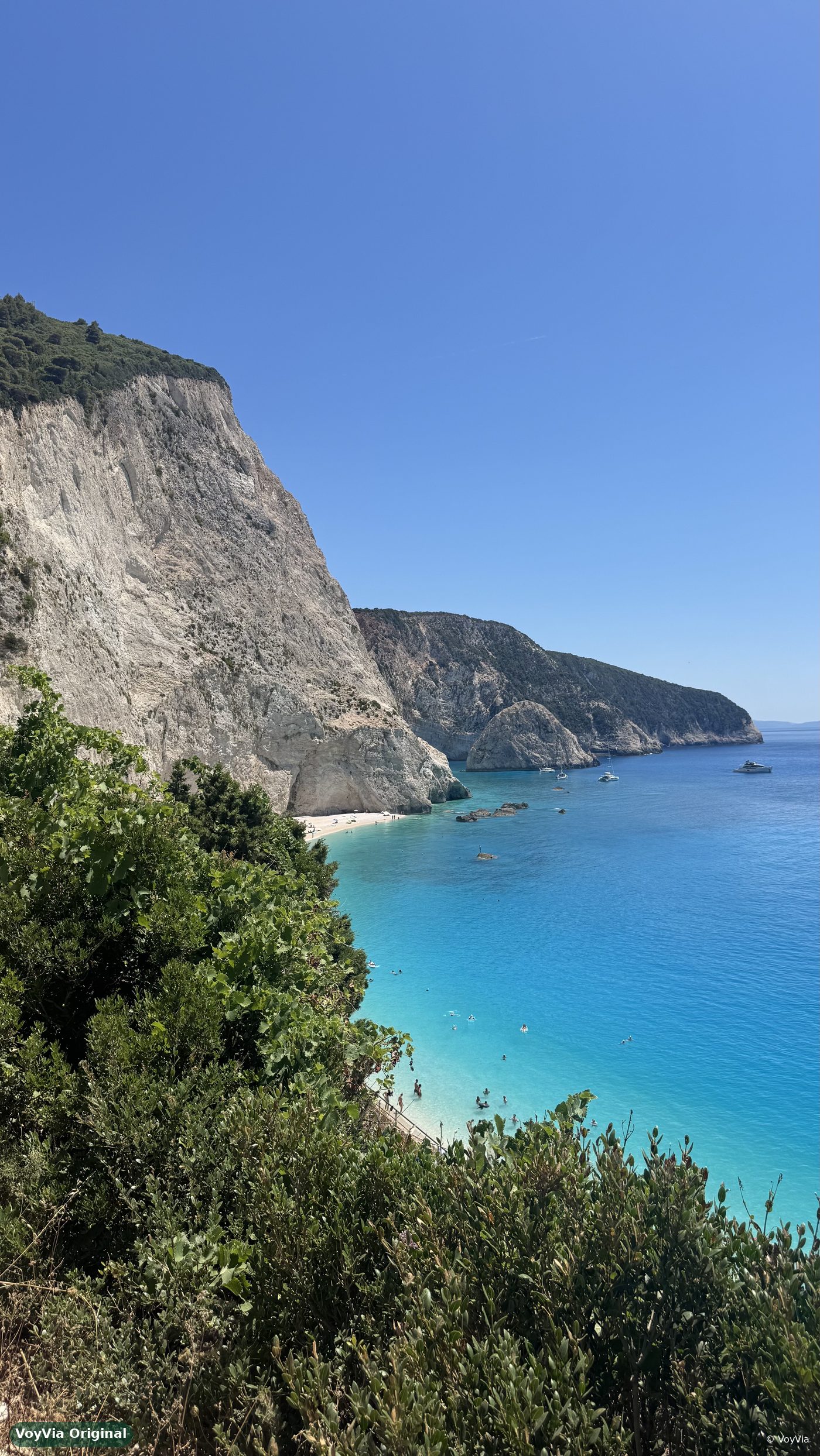 Boats in turquoise water in front of the white cliffs of Porto Katsiki, Lefkada, Greece.